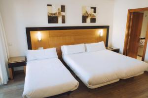 two beds in a hotel room with white sheets at Hotel Bonalba Alicante in El Campello