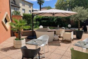 a patio with tables and chairs and an umbrella at Hôtel de Brienne in Toulouse