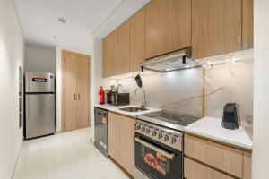 a kitchen with a stove and a stainless steel refrigerator at FIRST CLASS Studio Beach View Living Bliss in Ras al Khaimah