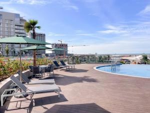 a patio with chairs and a swimming pool with a building at FIRST CLASS Studio Beach View Living Bliss in Ras al Khaimah