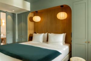 a bedroom with a large bed with two lights at Hôtel Casimir in Paris