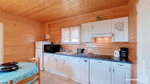 a kitchen with white cabinets and a white refrigerator at Chalet de la Gougère 3 in Chambon-sur-Lac +3 photos