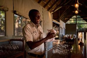 a man is standing at a bar holding a glass at Maasai Wild Adventure in Gatunga