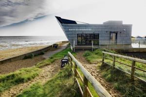 a building on the beach next to the ocean at Annie's Hideaway in Chapel Saint Leonards