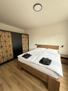 a bedroom with a bed with white sheets and a clock at Mid-Town Spacious Apartment in Banská Bystrica