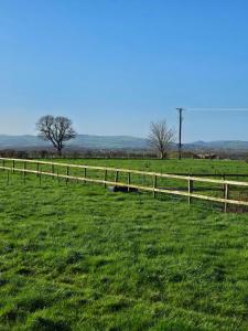 a wooden fence in a field with green grass at Ruth's Refresh Shropshire Country Retreat with Private Hot Tub & Stunning Views in Shrewsbury