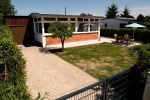 a house with a patio and a yard with a bench at Ferienbungalow Strandluft in Loissin +4 photos