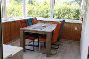a table and chairs in a room with windows at Ferienbungalow Strandluft in Loissin