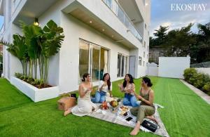 four women sitting on the grass in front of a house at EKOSTAY - Azure Villa in Lonavala +25 photos