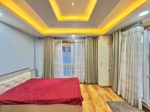 a bedroom with a bed with a red comforter at Triluna Apartments in Pātan