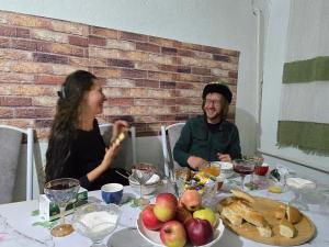 a man and a woman sitting at a table at Dastans Homestay, Bed and Breakfast & Horse riding in Kyzart