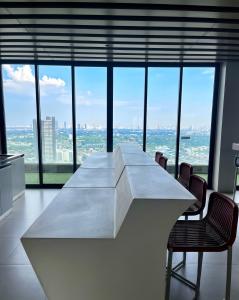 a large white table with chairs in a room with windows at Comfy Plum West Gate Condo 1 BR in Ban Bang Krabu
