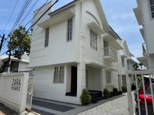 a white building with a sign in front of it at Zara Homes in Alleppey