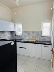 a kitchen with white cabinets and black counter tops at Zara Homes in Alleppey