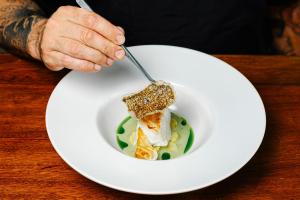 a person eating a plate of food with a fork at Hotel EL GRIFO in San Bartolomé