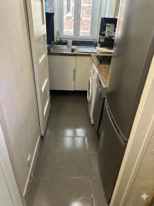 a kitchen with a refrigerator and a tile floor at Paris Défense T2 Design in Suresnes