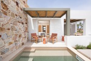 eine Terrasse mit Tisch und Stühlen und einer Steinmauer in der Unterkunft Espera Suites in Kimolos