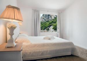 a bedroom with a bed with a lamp and a window at Hotel Pulicinu in Baja Sardinia