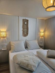two beds in a bedroom with two lights on the wall at Skip Inn Strandhuisjes in Katwijk aan Zee