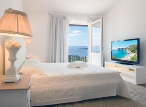 a white bedroom with a bed and a television at Hotel Pulicinu in Baja Sardinia +73 photos