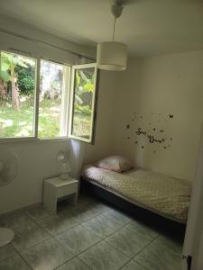 a small room with a bed and two windows at Maison agréable, emplacement idéal in Sainte-Suzanne
