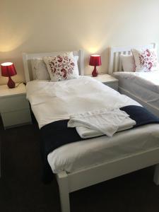 um quarto com 2 camas com lençóis brancos e almofadas em The Horse and Jockey em Stapleford