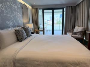 a bedroom with a large bed and a balcony at The Quarter Chaophraya by UHG - Riverfront Hotel, Walk to ICONSIAM in Bangkok