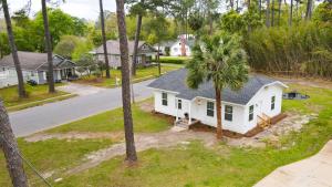 an aerial view of a white house with a palm tree at Mimosa Cottage - Thomasville Charm in Thomasville