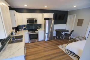 a kitchen with white cabinets and stainless steel appliances at Modern Queen Studio At The Victorian - Unit B in Muskegon +9 photos