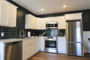 a kitchen with white cabinets and a stainless steel refrigerator at Modern Queen Studio At The Victorian - Unit B in Muskegon