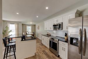 a kitchen with white cabinets and a stainless steel refrigerator at Mimosa Getaway - Thomasville Fun! in Thomasville