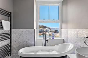 a white bath tub in a bathroom with a window at Leader Suite - Sea View - Free Wi-Fi in Brixham +11 photos