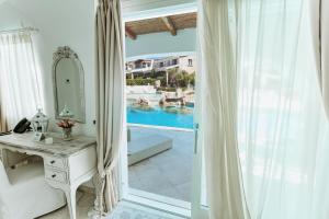 a bedroom with a mirror and a dressing table and a pool at Hotel Pulicinu in Baja Sardinia