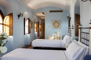 two beds in a bedroom with blue walls at Hotel Tugasa Arco de la Villa in Zahara de la Sierra