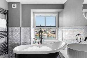 a white bathroom with a tub and a window at Vigilance Suite - Free Wi-Fi - Sea View in Brixham