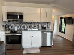 a kitchen with white cabinets and stainless steel appliances at Victorian Queen Getaway Unit C Washerdryer in Muskegon +13 photos
