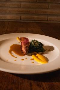 a white plate with a piece of meat and vegetables at Poggio dei cavalieri in Boccea +26 photos