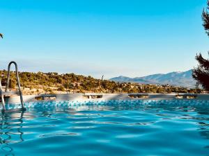 a swimming pool with blue water and mountains in the background at Mountain pool house in Varnávas