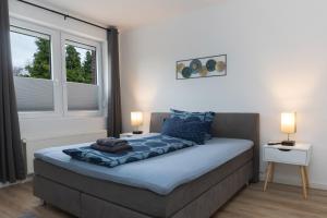 a bedroom with a bed with two lamps and a window at Infinity Stay Apartmenthaus am Park in Wilhelmshaven