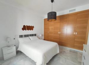 a bedroom with a white bed with a wooden headboard at Living Sevilla & Parking gratis in Seville