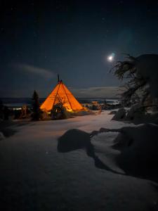 a lit up tent in the snow at night at Tipi Mountain Camp in Sorsele +6 photos