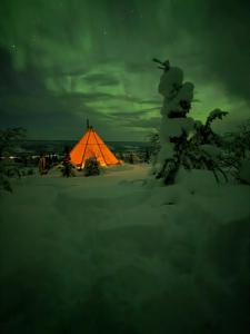a tent is lit up in the snow at night at Tipi Mountain Camp in Sorsele