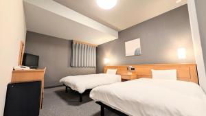 a hotel room with two beds and a television at Hotel Route-Inn Aomori Ekimae in Aomori