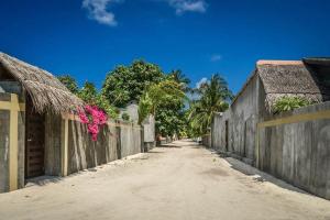 an empty street with a fence and palm trees at Dimora Blu Maldives in Dharavandhoo