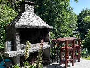 a stone fireplace with a table and a stool at Fethy`s House in Brod na Kupi
