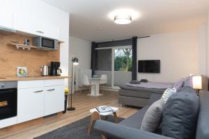 a living room with a couch and a kitchen at Infinity Stay Apartmenthaus am Park in Wilhelmshaven