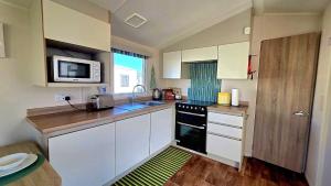 a small kitchen with a sink and a microwave at Tea & Toast Cottage Seton Sands in Port Seton
