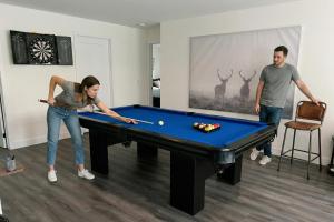a woman and a man playing a game of pool at Chalet Boréale with Private Spa & Billiards, Golf & Carling Lake in Brownsburg