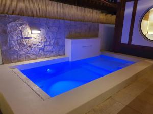 a blue pool in a room with a stone wall at Hyu Stay in Gyeongju