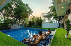 a group of people sitting in chairs by a swimming pool at EKOSTAY - Casa De Reva in Lonavala